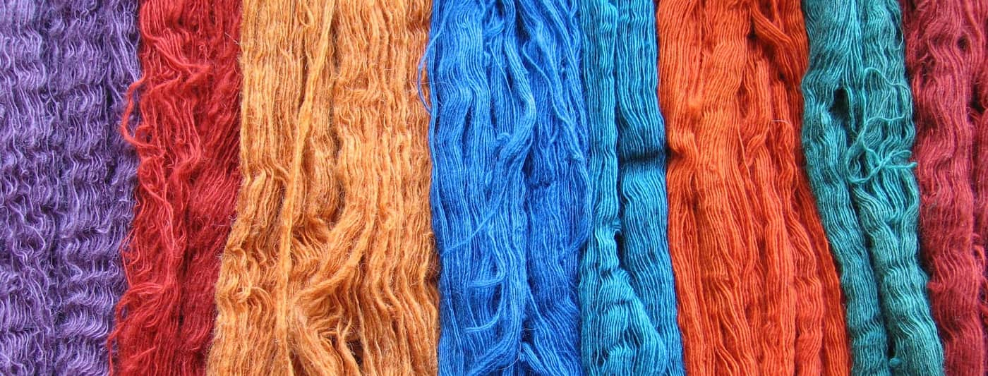 Madeixes de llana tenyides amb tints naturals en taronja, blau i vermell