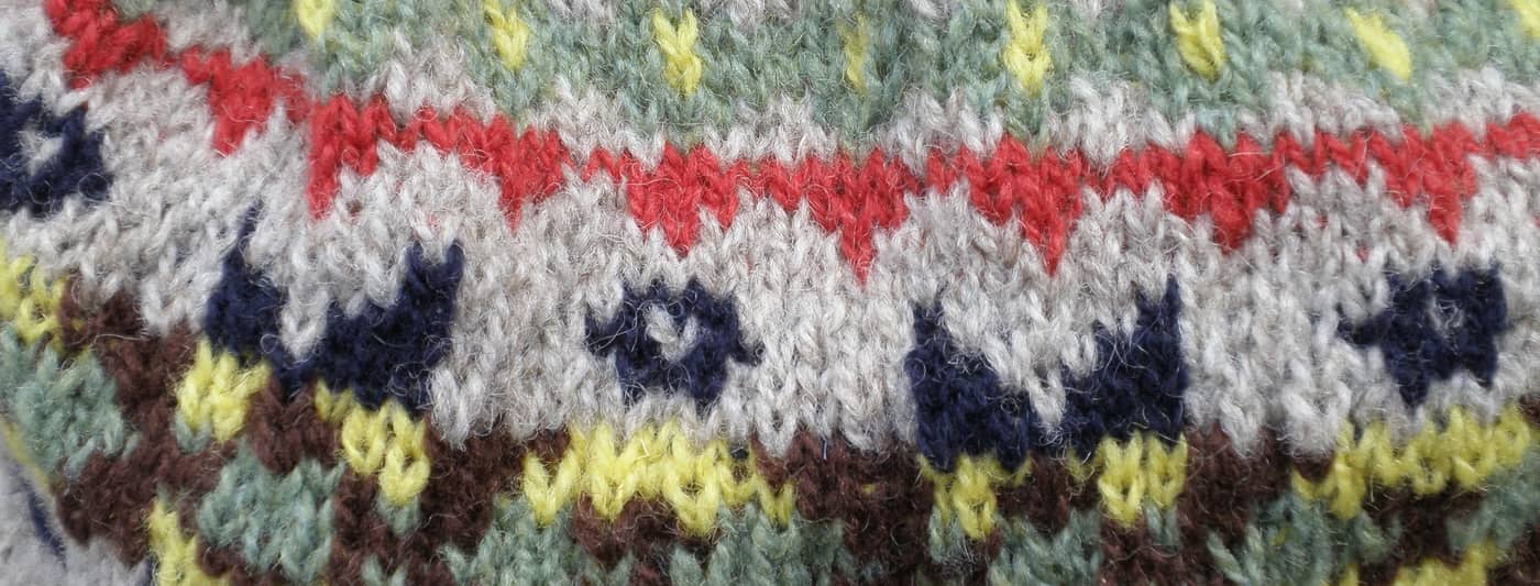 Detall d’un jersei de punt Fair Isle amb motius vermells, grocs i blaus