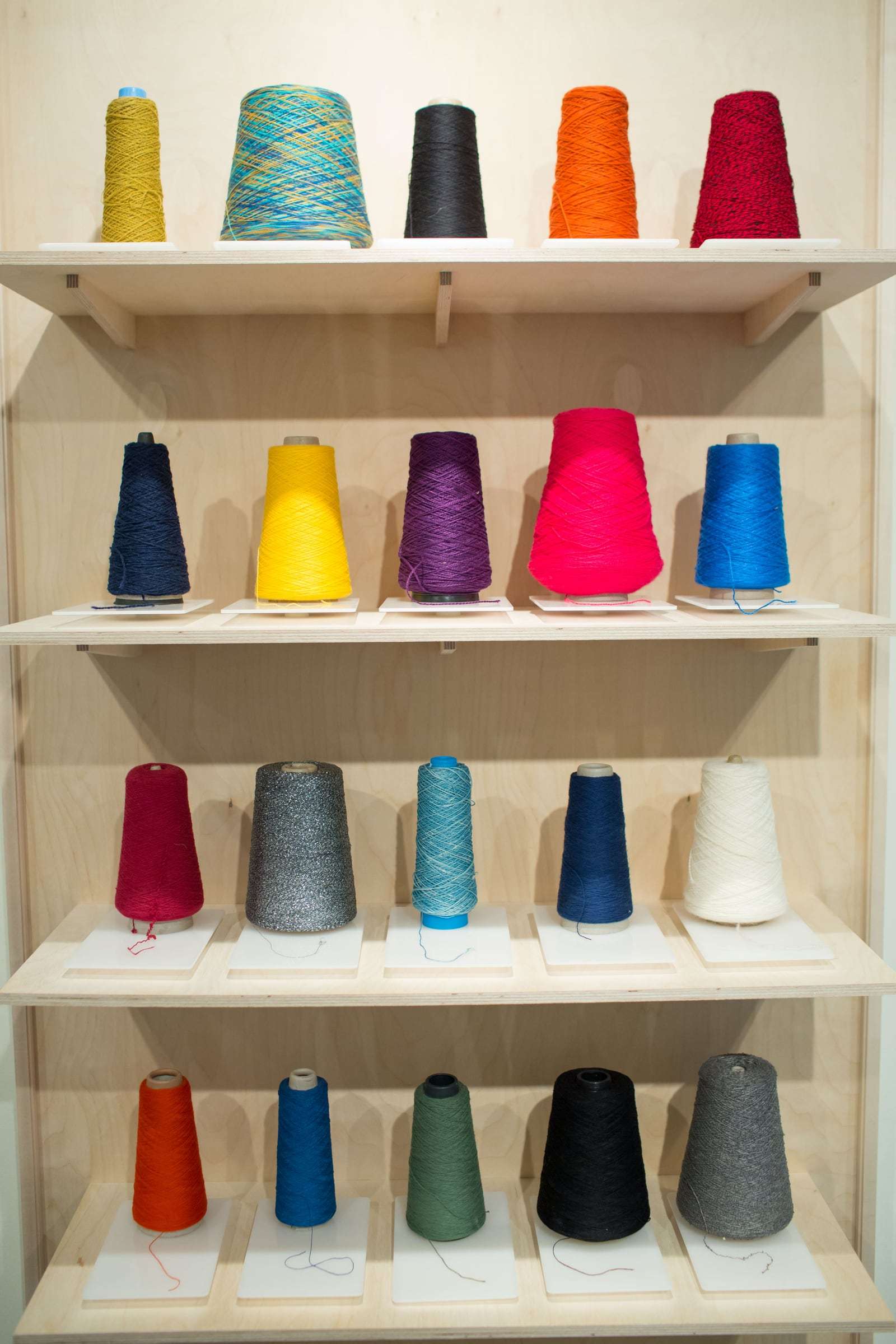 Cons de fil de colors en una prestatgeria de fusta