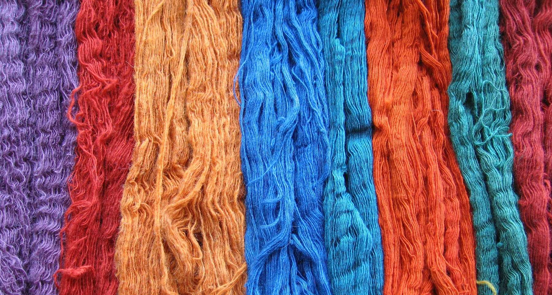 Madeixes de llana tenyides amb tints naturals en taronja, blau i vermell