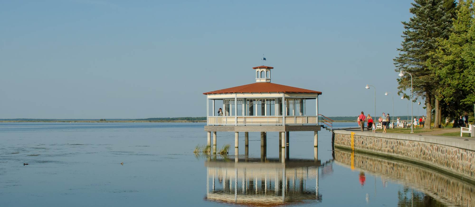 Pavelló de fusta del passeig de Haapsalu reflectit a la badia en calma