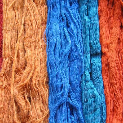 Madeixes de llana tenyides amb tints naturals en taronja, blau i vermell