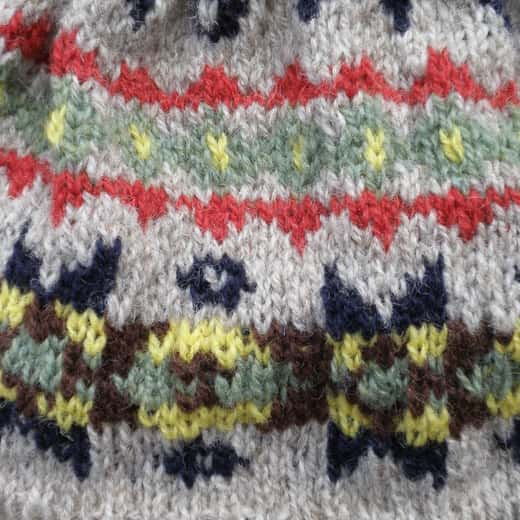 Detall d’un jersei de punt Fair Isle amb motius vermells, grocs i blaus