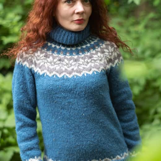 Dona amb un lopapeysa blau i canesú de motius grisos i blancs