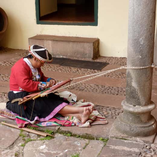 Teixidora quítxua treballant en un teler de cintura en un pati colonial de Cusco