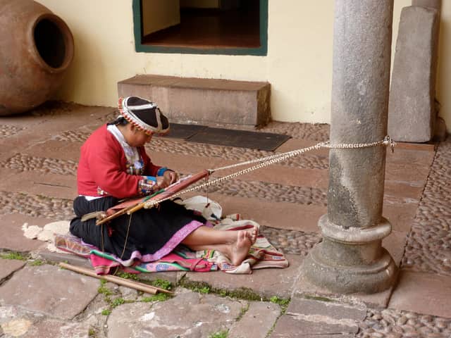 Teixidora quítxua treballant en un teler de cintura en un pati colonial de Cusco