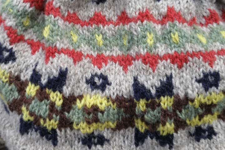 Detall d’un jersei de punt Fair Isle amb motius vermells, grocs i blaus