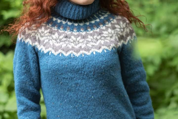 Dona amb un lopapeysa blau i canesú de motius grisos i blancs