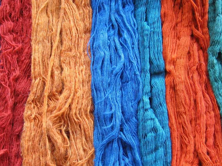Madeixes de llana tenyides amb tints naturals en taronja, blau i vermell