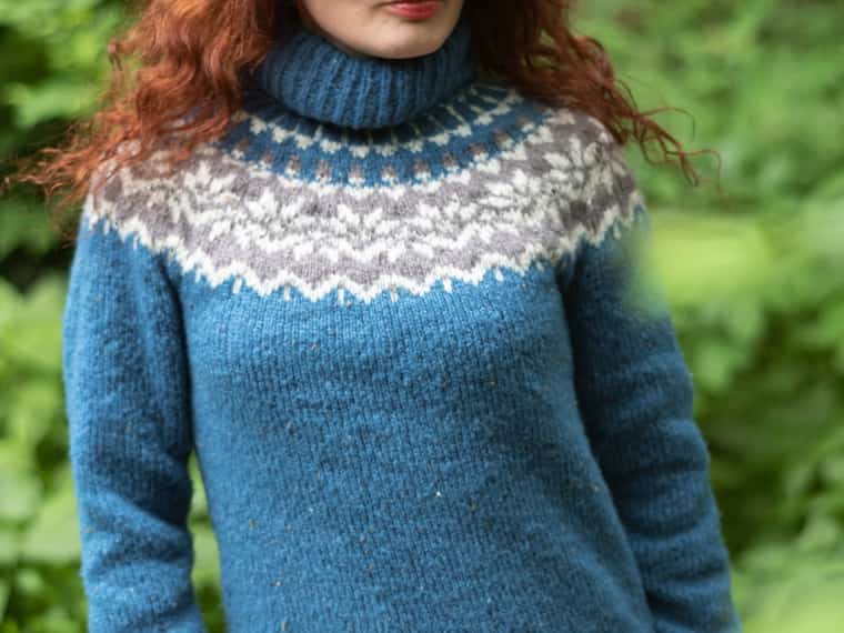 Dona amb un lopapeysa blau i canesú de motius grisos i blancs